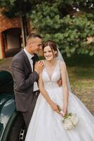 un hermoso novio abraza su novia en un lozano blanco vestir y sonrisas en un hermosa al aire libre ajuste. debajo el abierto cielo. alto calidad foto. un recién casado Pareja poses juntos en un soleado verano día. foto