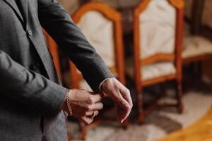 Hands button up the buttons on his shirt. The process of fastening the buttons on his white shirt. Close view. Groom buttons on his shirt cuffs. Morning of the groom photo