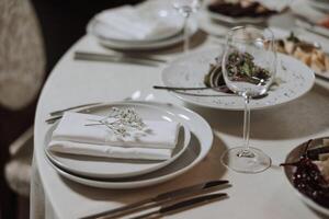 A view of wedding tables, attention to serving, with flower arrangements, expensive cutlery, plates with white napkins. photo