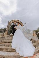 newly married couple.wind lifting long white bridal veil summer. The bride and groom embrace, the long veil flies in the wind photo