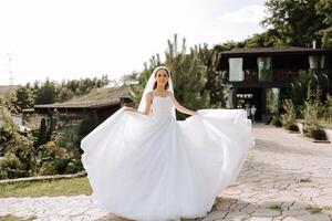 hermosa novia con un largo tren. el novia en un blanco vestir con un largo tren en naturaleza en un verano día. verano boda. foto