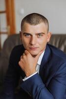 Portrait of a young groom at home before the wedding ceremony. A handsome man dressed in a classic suit. Male portrait. photo