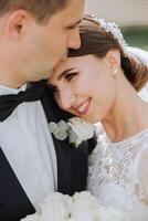 The groom kisses his bride on the temple against the background of beautiful nature on a summer day. Art. Selective focus. photo