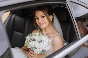 The bride looks out of the car window. Close-up portrait of a pretty shy bride in a car window. Bride smile emotions photo