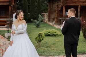 The bride is dressed in an elegant lush white wedding dress with a long veil and is ready for her groom. The first meeting of the bride and groom photo