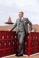 retrato de el novio en naturaleza en el verano. elegante alto novio en un elegante gris negocio traje. empresario en naturaleza. retrato de un exitoso hombre. Boda retrato de el novio. foto