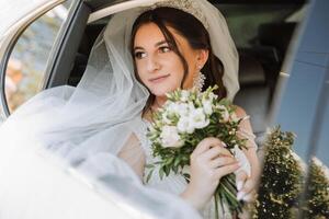 The bride looks out of the car window. Close-up portrait of a pretty shy bride in a car window. Bride smile emotions photo