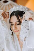 Beautiful bride in a dressing gown in the morning before the wedding ceremony. Incredible hairstyle of the bride. Natural and modern makeup. Portrait of a young bride in a dressing gown. photo