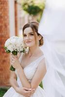 hermosa novia con Boda flores ramo, atractivo mujer en Boda vestido. contento recién casado mujer. novia con Boda maquillaje y peinado. sonriente novia. Boda día. maravilloso novia. casamiento. foto