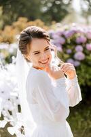 A beautiful brunette bride in an elegant robe is walking in a park with green grass and pink hydrangea flowers. Morning, meetings, wedding portrait of a cute girl. Photography and concept. Summer. photo