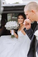 The bride looks out of the car window. Close-up portrait of a pretty shy bride in a car window. Bride smile emotions photo