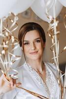 Beautiful bride in a dressing gown in the morning before the wedding ceremony. Incredible hairstyle of the bride. Natural and modern makeup. Portrait of a young bride in a dressing gown. photo