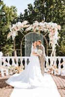 el novio pone en el de la novia Boda anillo durante el Boda ceremonia cerca el flor arco. verano Boda en naturaleza. ella dijo Sí. un conmovedor momento a el Boda ceremonia foto