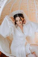 Beautiful bride in a dressing gown in the morning before the wedding ceremony. Incredible hairstyle of the bride. Natural and modern makeup. Portrait of a young bride in a dressing gown. photo