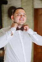 man in shirt dressing up and adjusting tie on neck at home. Wedding day concept,fashion, business, male style. photo