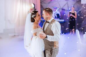 Wedding dance of the bride and groom. The first dance of the bride and groom in an elegant wedding hall with the use of heavy smoke and pyrotechnic lights, confetti. photo