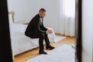 Portrait of a young groom at home before the wedding ceremony. A handsome man dressed in a classic suit. Male portrait. photo