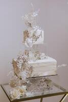 a two-tiered wedding cake decorated with flowers stands on a glasses table. Decorative wedding cake. Beauty is in the details. photo