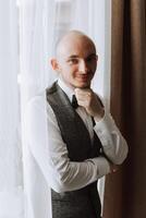 Portrait of a young groom at home before the wedding ceremony. A handsome man dressed in a classic suit. Male portrait. photo