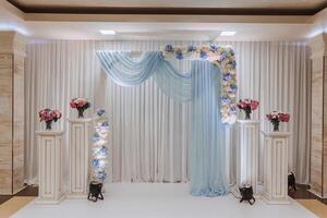 The photo zone at a wedding or birthday celebration is decorated with flowers and illuminated by artificial light