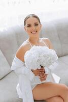 Beautiful bride in a dressing gown in the morning before the wedding ceremony. Incredible hairstyle of the bride. Natural and modern makeup. Portrait of a young bride in a dressing gown. photo