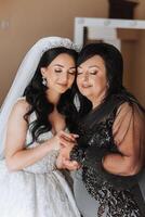 A beautiful and happy mother and her daughter, the bride, are standing next to each other. The best day for parents. Tender moments at the wedding. photo