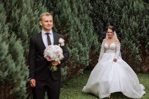 The bride is dressed in an elegant lush white wedding dress with a long veil and is ready for her groom. The first meeting of the bride and groom photo