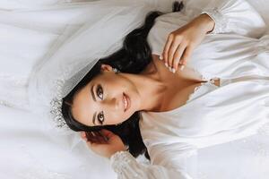 A beautiful young bride girl is lying in a beautiful robe. Morning of the bride before the wedding ceremony. photo