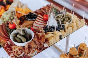 meat and cheese snacks on the buffet table. open-air buffet table, sandwiches on skewers before the start of the holiday. photo