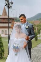 The bride is dressed in an elegant lush white wedding dress with a long veil and is ready for her groom. The first meeting of the bride and groom photo