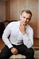 Portrait of a young groom at home before the wedding ceremony. A handsome man dressed in a classic suit. Male portrait. photo