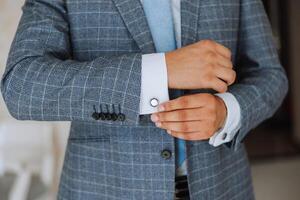 Hands button up the buttons on his shirt. The process of fastening the buttons on his white shirt. Close view. Groom buttons on his shirt cuffs. Morning of the groom photo