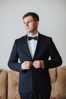 Portrait of a young groom at home before the wedding ceremony. A handsome man dressed in a classic suit. Male portrait. photo