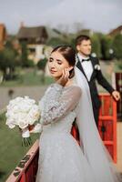 The bride is dressed in an elegant lush white wedding dress with a long veil and is ready for her groom. The first meeting of the bride and groom photo