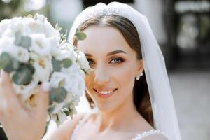 Beautiful bride with wedding flowers bouquet, attractive woman in wedding dress. Happy newlywed woman. Bride with wedding makeup and hairstyle. Smiling bride. Wedding day. Gorgeous bride. Marriage. photo