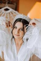 Beautiful bride in a dressing gown in the morning before the wedding ceremony. Incredible hairstyle of the bride. Natural and modern makeup. Portrait of a young bride in a dressing gown. photo