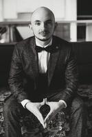 Portrait of a young groom at home before the wedding ceremony. A handsome man dressed in a classic suit. Male portrait. photo
