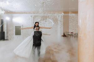 Wedding dance of the bride and groom. The first dance of the bride and groom in an elegant wedding hall with the use of heavy smoke and pyrotechnic lights, confetti. photo