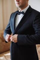 Man fastens the buttons. The groom in a suit. Close up. Man is buttoning his vest. Perfect to the last detail. Modern businessman. photo