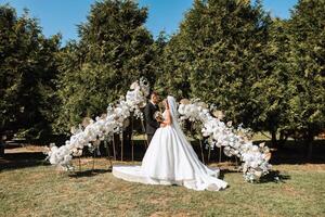 el novio pone en el de la novia Boda anillo durante el Boda ceremonia cerca el flor arco. verano Boda en naturaleza. ella dijo Sí. un conmovedor momento a el Boda ceremonia foto