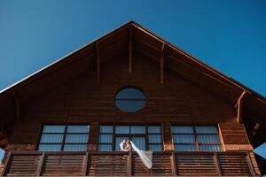 a newly married couple. the wind lifts a long white veil in summer. The bride and groom are hugging, a long veil is blowing in the wind. The newlyweds kiss on the balcony of the restaurant photo