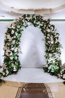 The photo zone at a wedding or birthday celebration is decorated with flowers and illuminated by artificial light