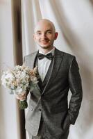 Portrait of a young groom at home before the wedding ceremony. A handsome man dressed in a classic suit. Male portrait. photo