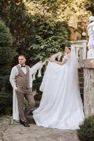 The bride is dressed in an elegant lush white wedding dress with a long veil and is ready for her groom. The first meeting of the bride and groom photo