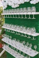 Green stand with champagne glasses. Many glasses for guests, preparation for the celebration. Details photo