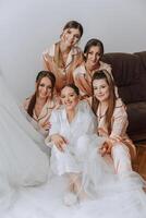 A beautiful bride and her bridesmaids are having fun in the morning. Wedding celebration. Happy girls at their best friend's wedding. A beautiful and elegant bride with her bridesmaids photo