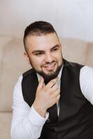 Portrait of a young groom at home before the wedding ceremony. A handsome man dressed in a classic suit. Male portrait. photo