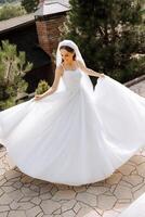 Beautiful bride with a long train. The bride in a white dress with a long train in nature on a summer day. Summer wedding. photo