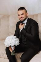 Portrait of a young groom at home before the wedding ceremony. A handsome man dressed in a classic suit. Male portrait. photo