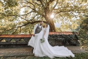 the groom passionately kisses the bride leaning her as if in a dance against the background of nature on a warm summer day. photo